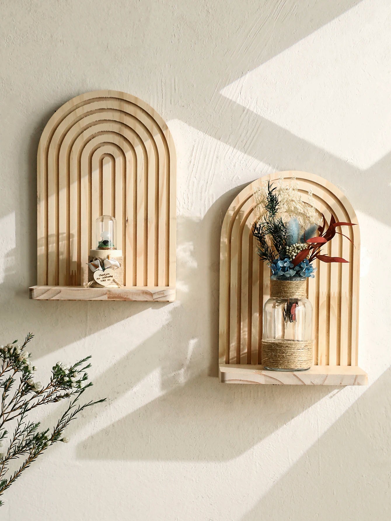 Two arch-shaped wall shelves with decorative items against a light wall.