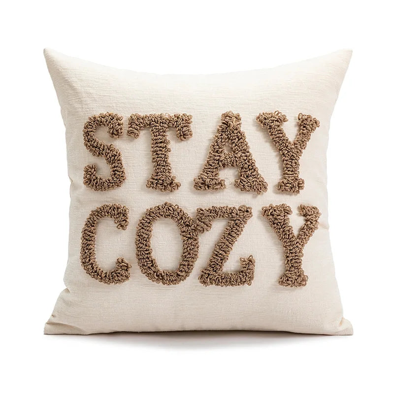 Beige pillow with 'STAY COZY' text on a white background