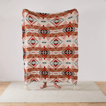 Patterned Bohemian blanket draped over a person on a light wooden floor with a white wall background