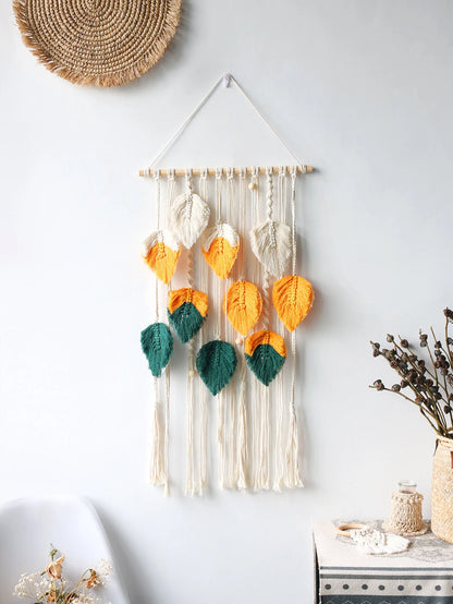 Decorative wall hanging with colorful leaves on a white wall.