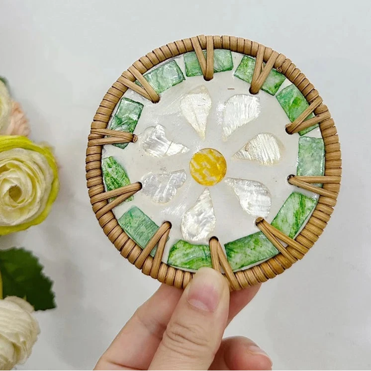 Round decorative boho coaster with green and white design held by a hand against a light background