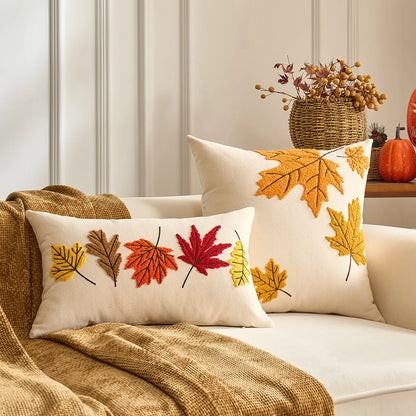 Decorative pillows with autumn leaf patterns on a couch. Fall maple leaf and pumpkin throw pillow cover for Thanksgiving decor