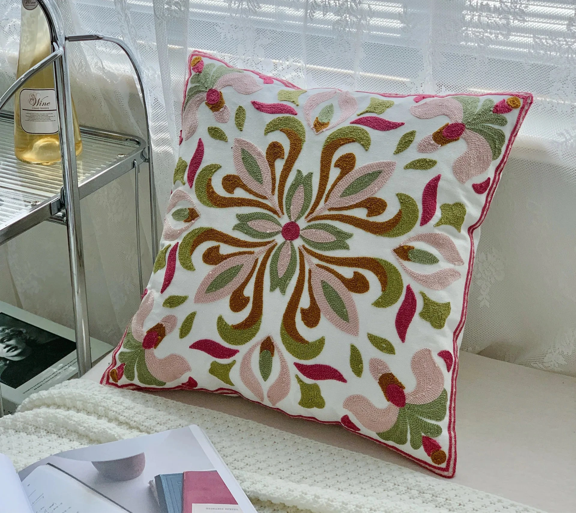 Decorative pillow with floral pattern on a couch next to a bottle of wine. floral embroidery on linen cotton cushion cover – boho home decor accent