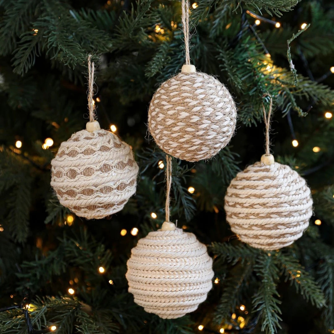 Textured spherical ornaments hanging on a Christmas tree with lights.