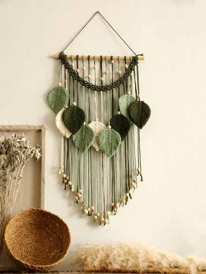 Decorative leaf macrame wall hanging with green leaves and string on a neutral background