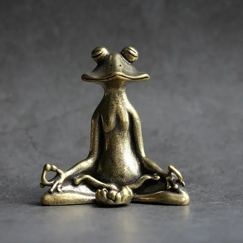Bronze frog statue in a meditative pose on a gray background