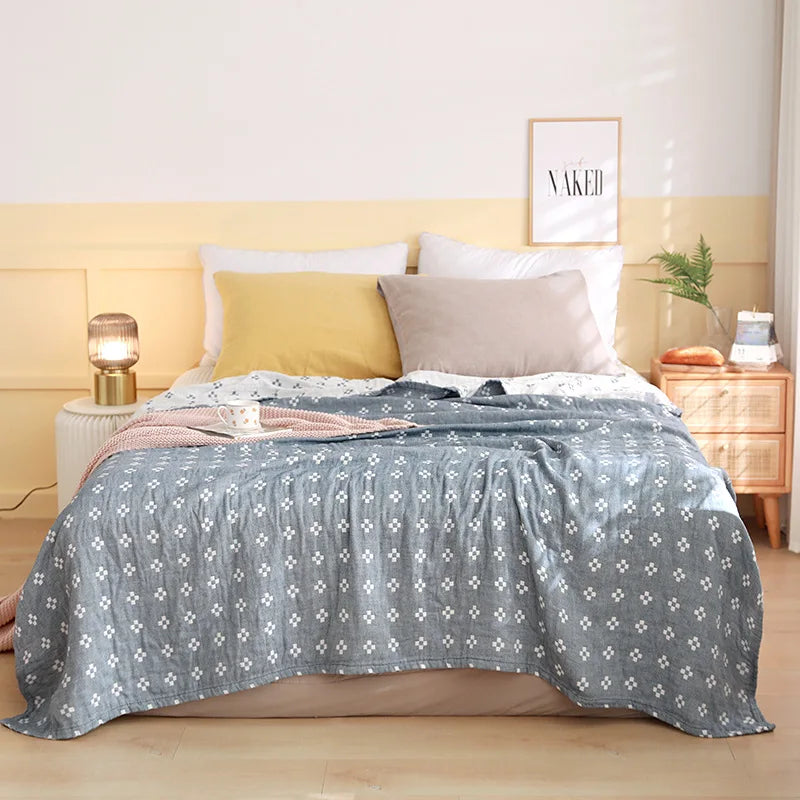 Bedroom with a bed covered in a gray floral patterned comforter, yellow headboard, and nightstands. Boho Lightweight microfiber summer blanket for bed or sofa, cooling breathable throw for home, dorm, or office naps with geometric jacquard pattern.