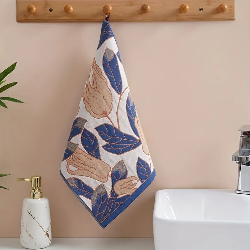 Decorative tea towel with leaf pattern hanging on a wooden towel rack above a sink.