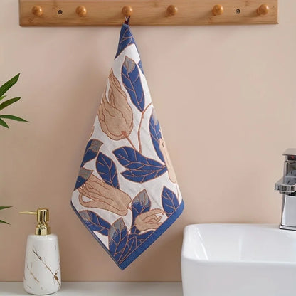 Decorative tea towel with leaf pattern hanging on a wooden towel rack above a sink.
