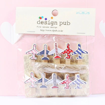 Packaged airplane-shaped paper clips with 'design pub' branding on a pink background
