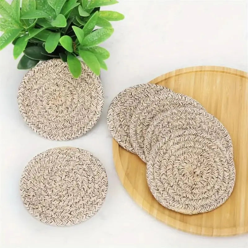 Set of woven coasters on a wooden surface with a plant in the background Set of cotton drink coasters – eco-friendly housewarming gift idea