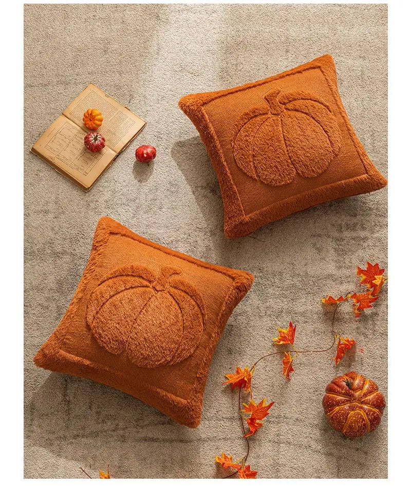 Two orange pumpkin-shaped cushions on a textured surface with decorative elements. Halloween pumpkin plush pillow cover for sofa and bed decor.