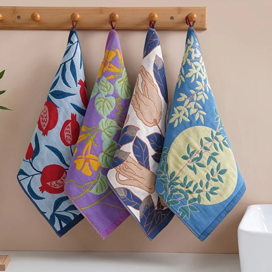 Four colorful tea towels with floral and nature designs hanging on a wooden rack.