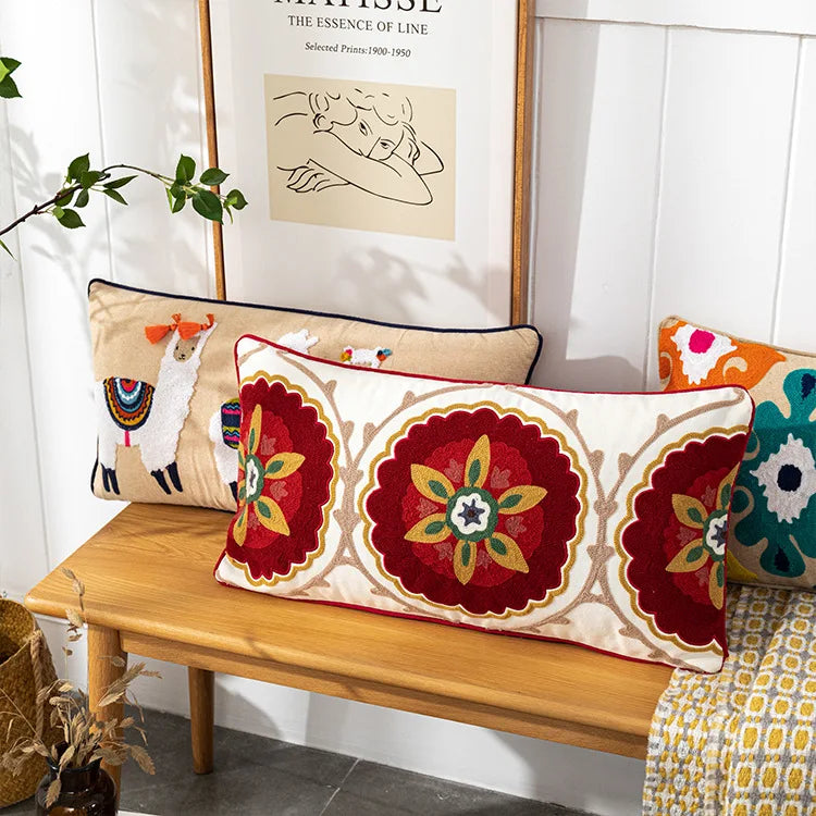 Decorative pillows on a wooden bench with a white wall and plant in the background. Bohemian embroidered throw pillow cover with geometric design, cotton-blend cushion for sofa, bed, or modern home decor.