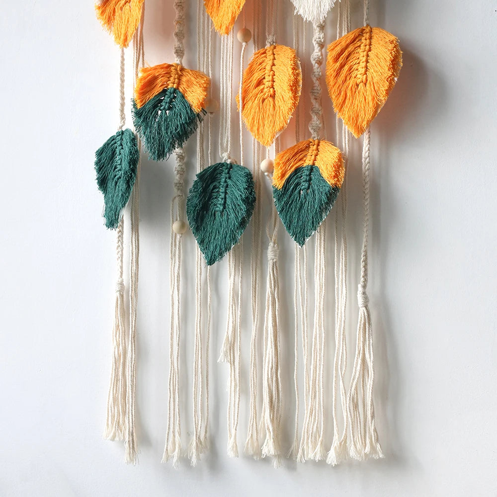 Decorative wall hanging with orange and green leaf-shaped tassels on a white background
