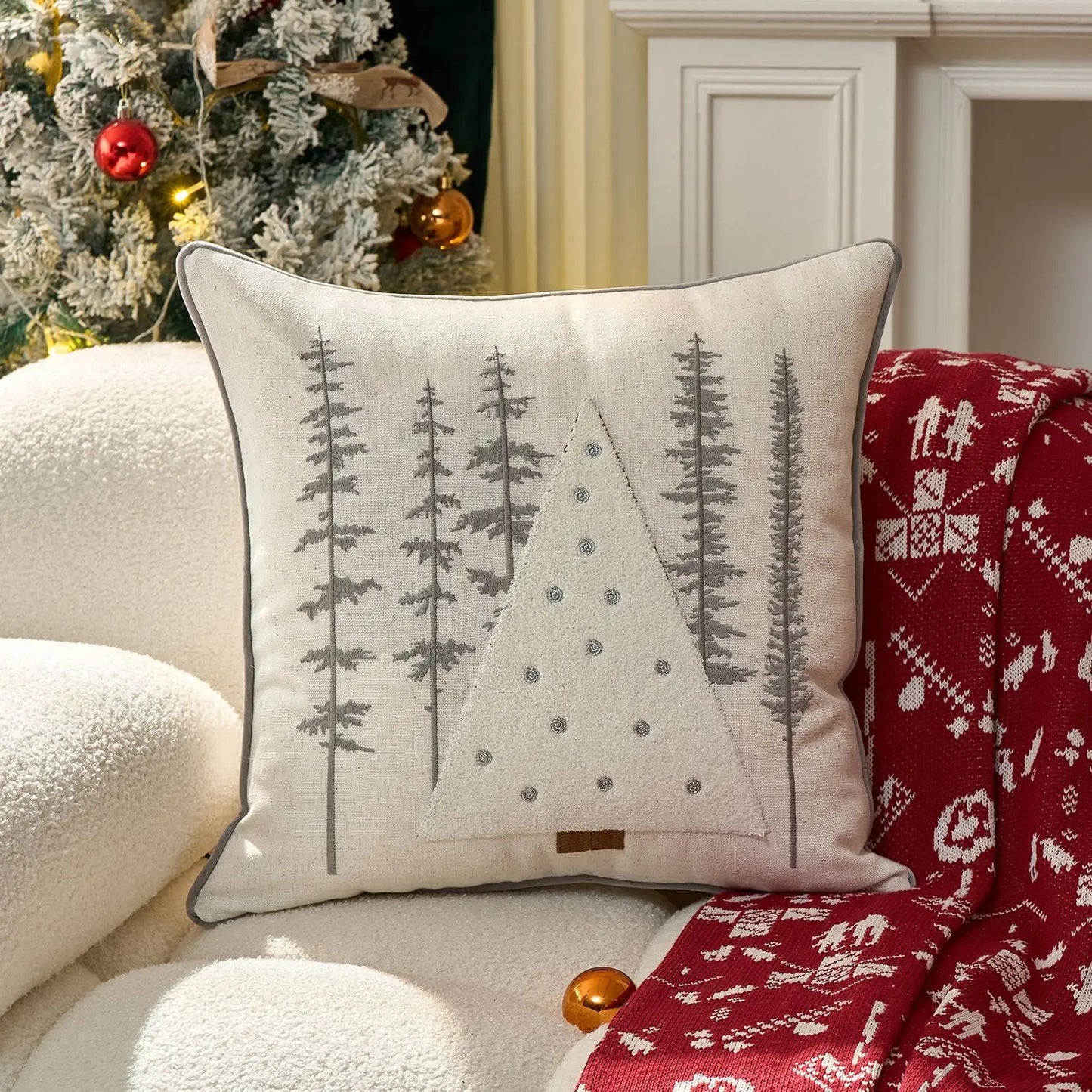 Decorative pillow with tree pattern on a couch next to a Christmas tree
