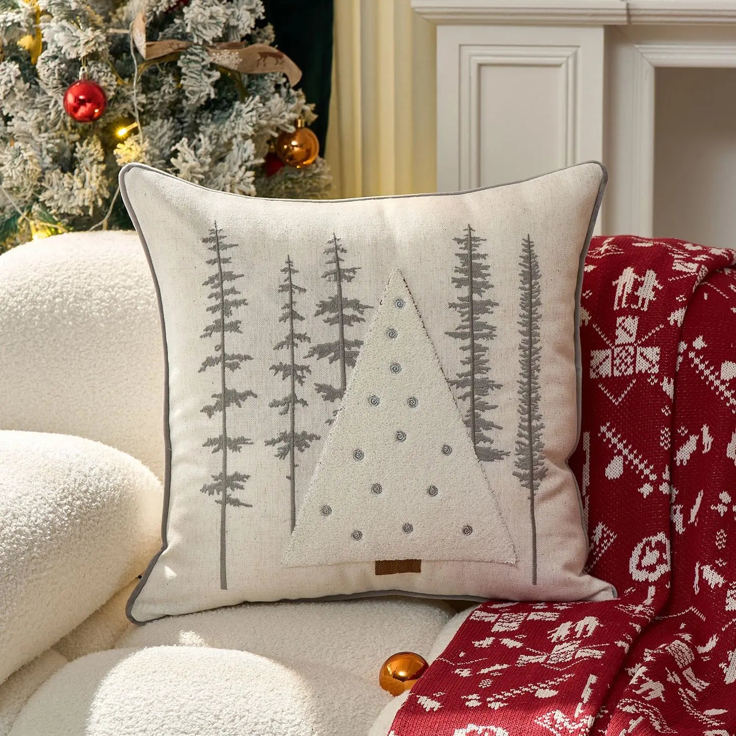 Decorative pillow with tree pattern on a couch next to a Christmas tree