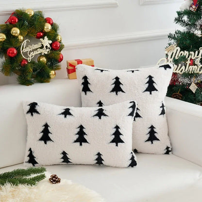 White pillows with black tree patterns on a white couch with Christmas decorations.