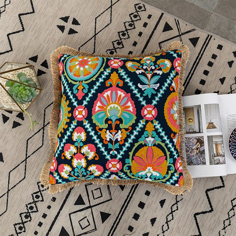 Decorative pillow with colorful pattern on a geometrically patterned rug. Bohemian embroidered throw pillow cover with geometric design, cotton-blend cushion for sofa, bed, or modern home decor.