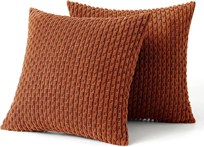 Two brown orange rust textured pillows on a white background