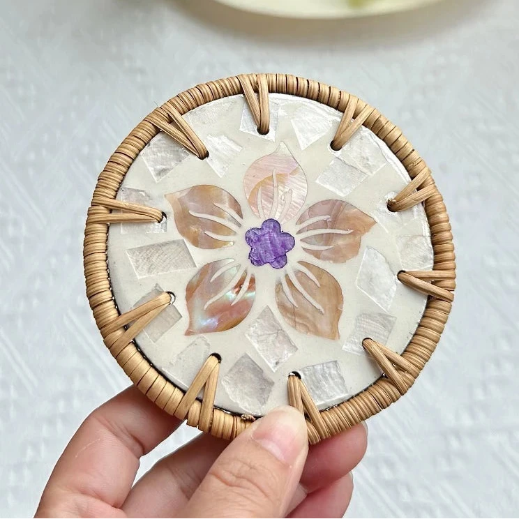 Round boho coaster with floral design held by a hand on a light background
