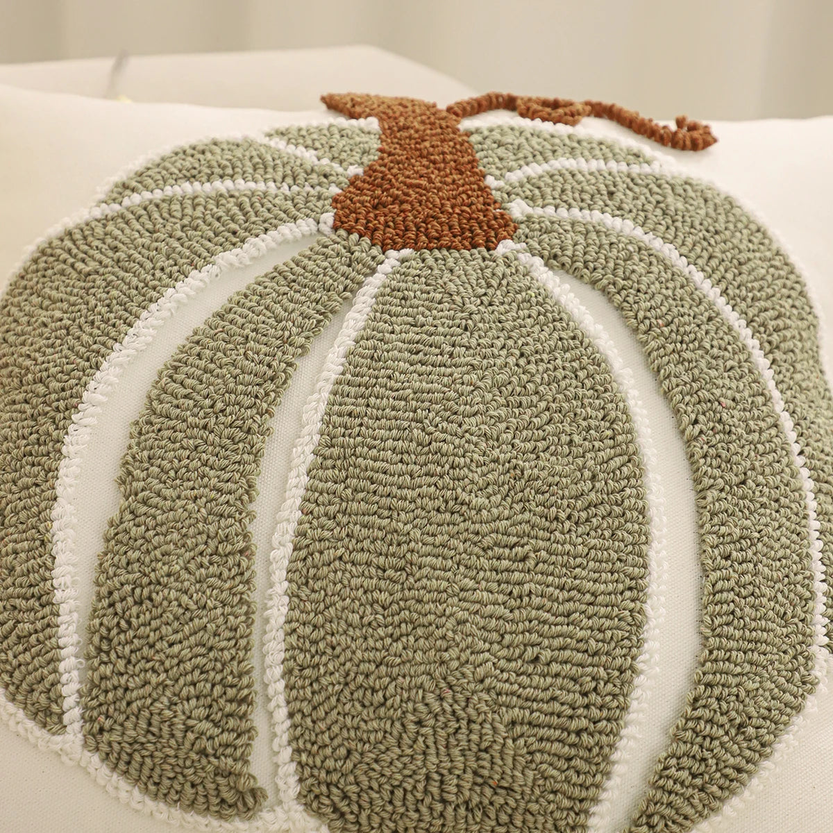 Textured pumpkin-shaped rug with a brown stem on a white background. Festive fall pillow cover for Halloween and Thanksgiving décor