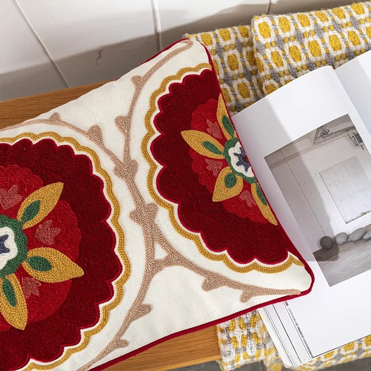 Decorative rug with floral patterns on a wooden surface. Bohemian embroidered throw pillow cover with geometric design, cotton-blend cushion for sofa, bed, or modern home decor.