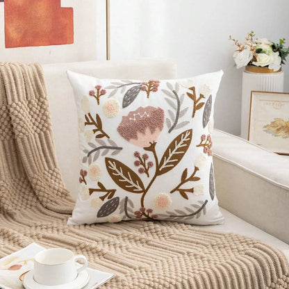 Decorative pillow with floral pattern on a couch with a blanket and cup. Embroidered flower pillow cover, 17.7-inch square canvas cushion case with floral design for sofa, bed, and boho home decor