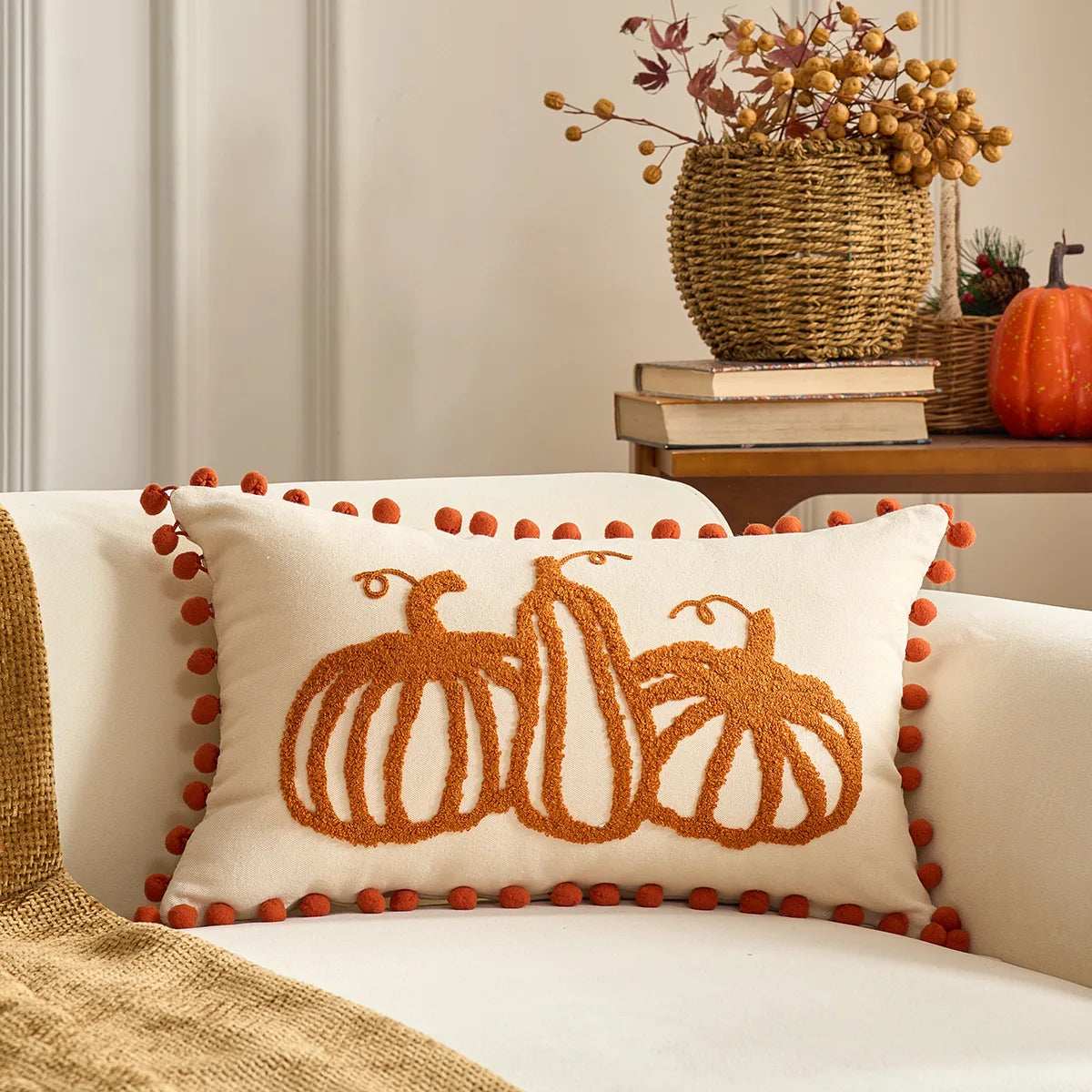 Decorative pillow with pumpkin design on a couch, with a vase of flowers and books in the background. Halloween and Thanksgiving decorative pillow cover For Fall.