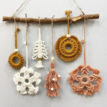 Set of macrame wall hangings on a wooden branch against a light background