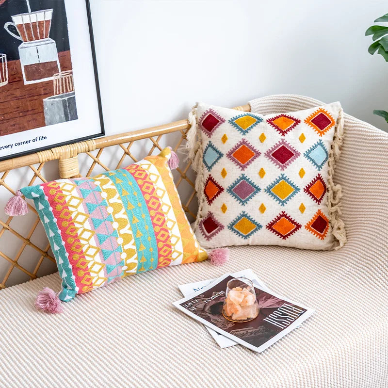 Decorative pillows on a couch with a magazine and framed artwork in the background.