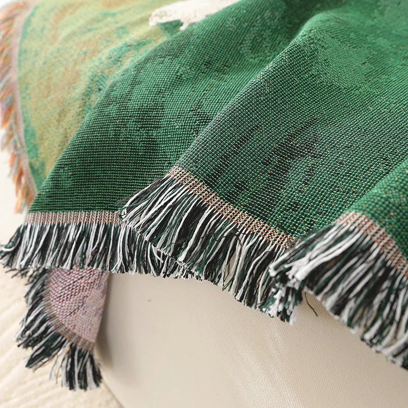Close-up of a green fabric with fringes on a beige background Grassland sheep tassel blanket, woven scenic throw for sofa, bed, or outdoor picnic, boho-inspired home decor blanket.