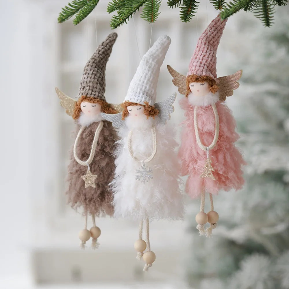 Three fairy figurines with different colored dresses hanging from a branch.