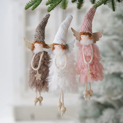 Three fairy figurines with different colored dresses hanging from a branch.
