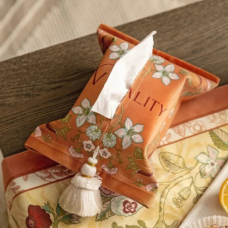 Floral-patterned tissue box on a decorative tablecloth with a white napkin. boho home decor, reusable tissue bag, cotton tassel tissue holder, plush tissue organizer, bathroom tissue box cover, car tissue case, American style tissue pouch, soft fabric tissue holder, decorative tissue box, housewarming gift, eco-friendly storage