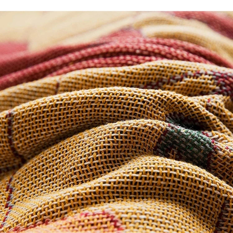 Close-up of textured fabric with a checkered pattern in red, yellow, and green. Travel-inspired cotton plaid bed cover and decorative boho blanket