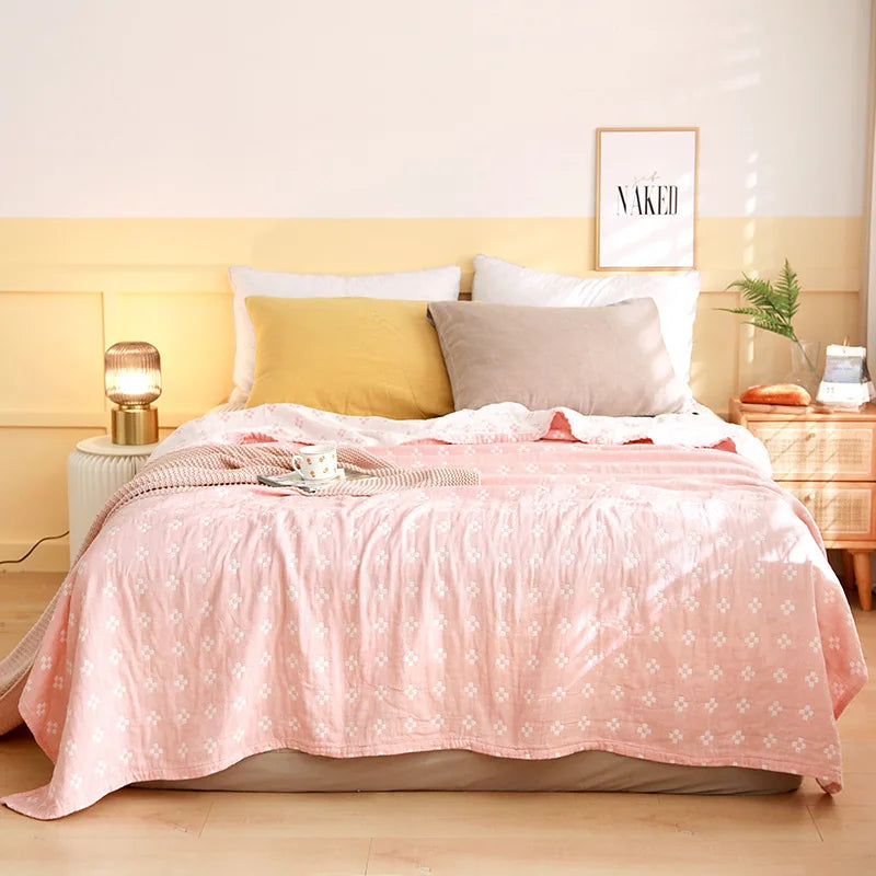 Bedroom with pink comforter, pillows, and nightstands. Boho Lightweight microfiber summer blanket for bed or sofa, cooling breathable throw for home, dorm, or office naps with geometric jacquard pattern.