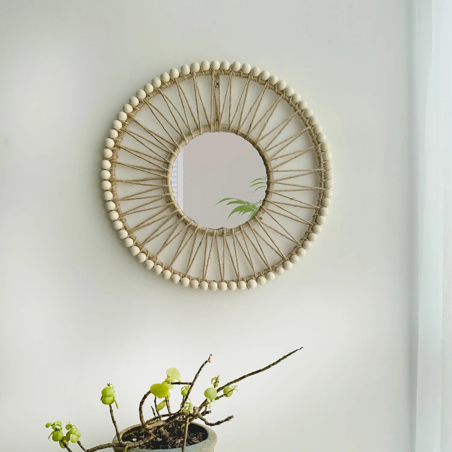 Round decorative mirror with wooden beads on a white wall Hand-woven Nordic round decorative mirror with Lafite grass frame and hemp rope, boho wall hanging for living room, entryway, or bedroom decor