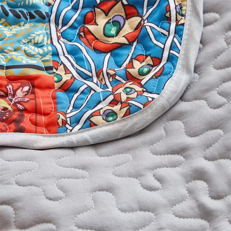 Close-up of a colorful fabric with owl patterns on a textured gray surface. Lightweight boho quilted bedspread set with pillow shams, soft all-season coverlet for queen, king, full, or twin beds in modern cloud pattern design.