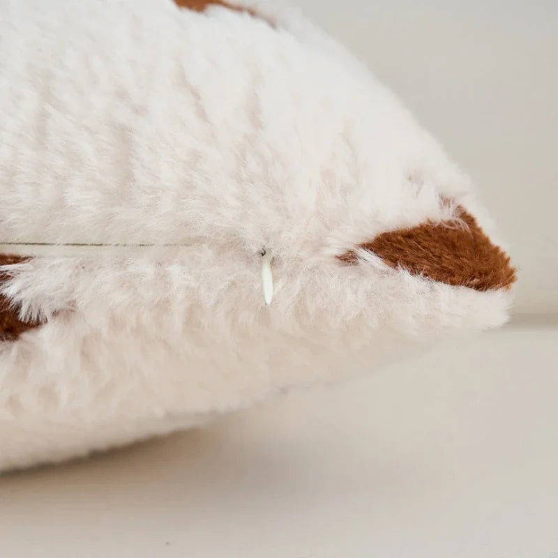 Close-up of a plush pillow with white and brown fur on a light background