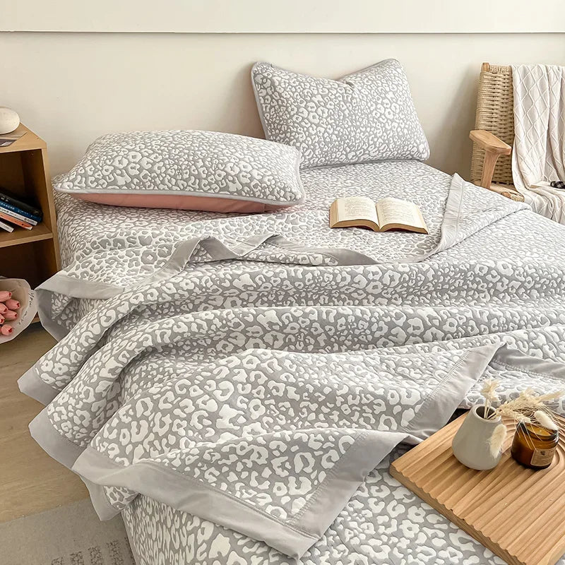 Bed with gray leopard print bedding and pillows in a bedroom setting. Boho breathable lightweight summer spring fall blanket quilt bedspread 