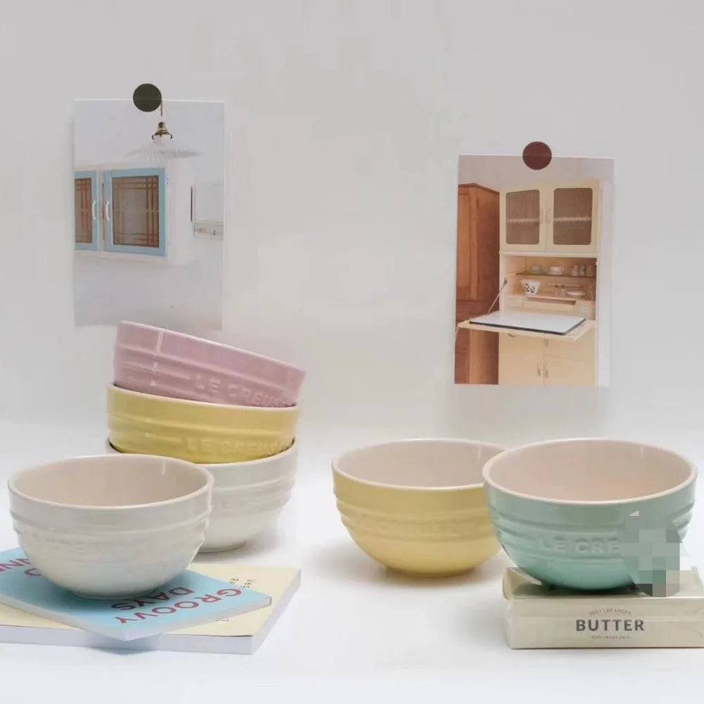 Set of colorful ceramic bowls on a white surface with kitchen-themed decor. Gradient ceramic rice bowl in bright colors, bone china soup and noodle bowl, dessert and pudding kitchen tableware for boho home dining