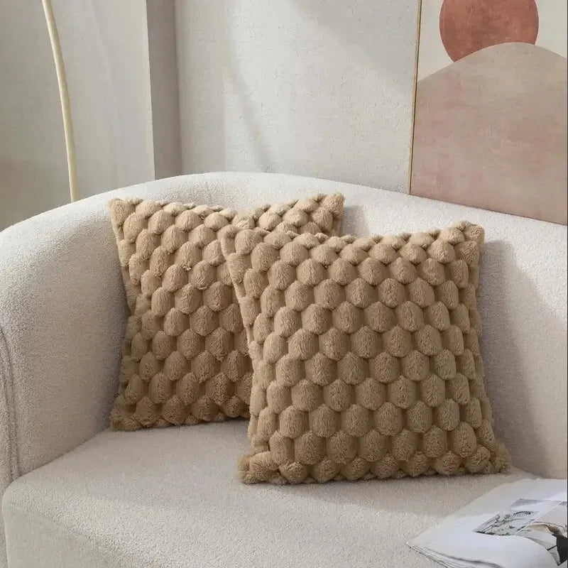 Two textured beige pillows on a light-colored sofa with a neutral background