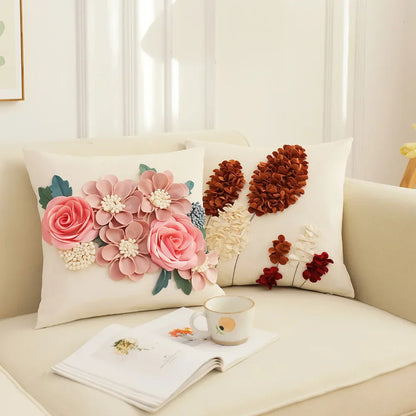 Decorative pillows with floral and pinecone designs on a couch with a cup and book. French style floral embroidered patchwork pillow cover for sofa decor