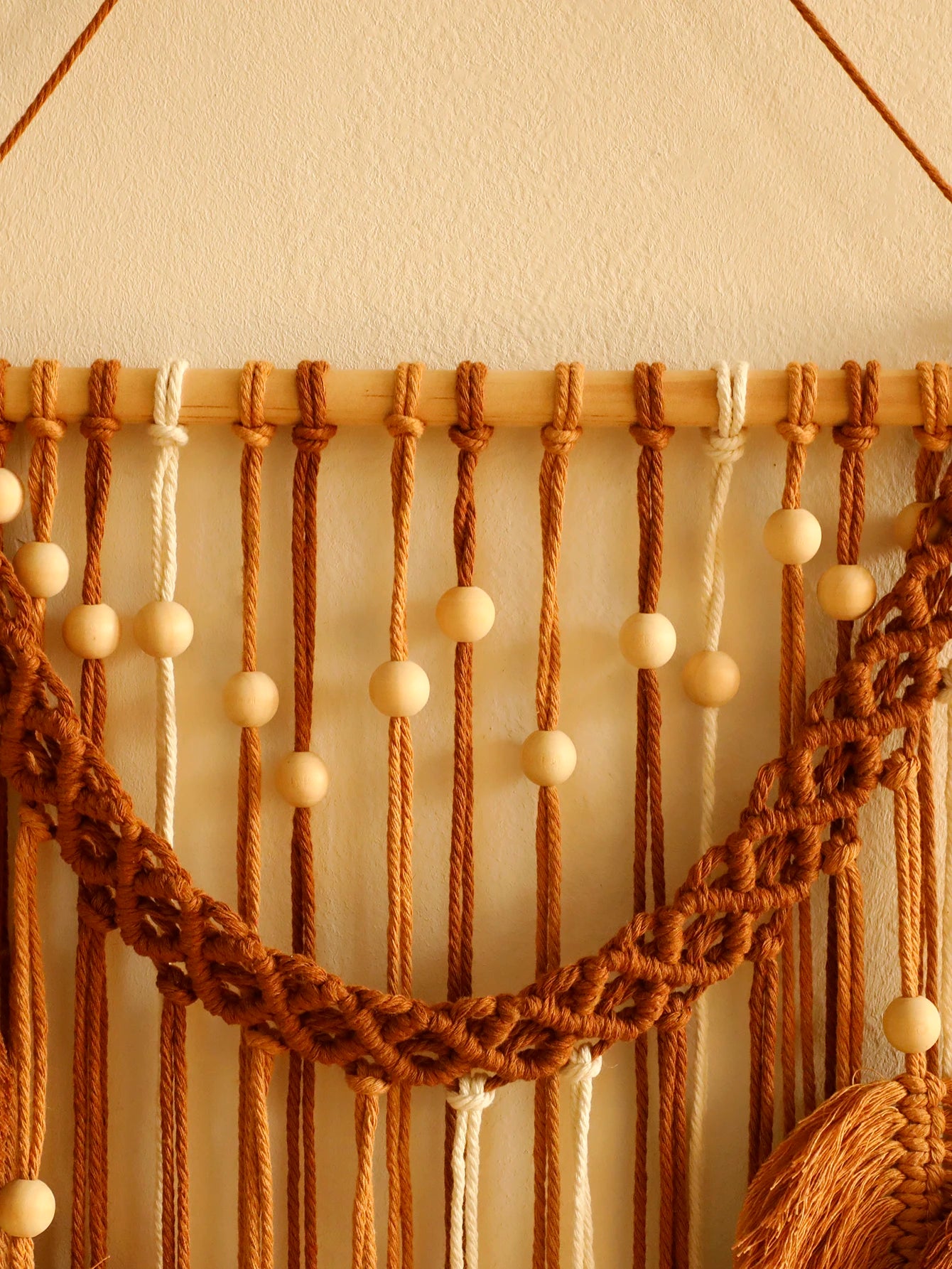 Macrame wall hanging with wooden beads on a neutral background