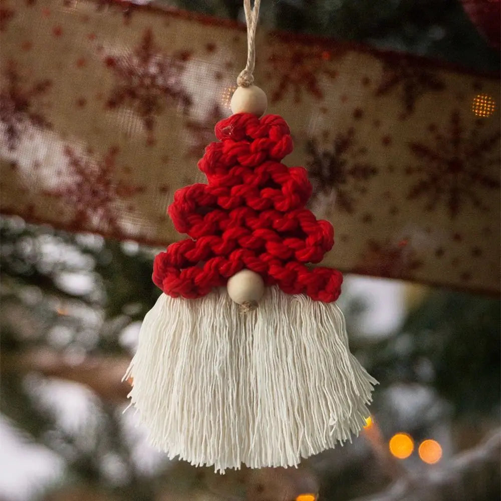 Knitted gnome macrame ornament with red hat and white beard hanging on a Christmas tree.