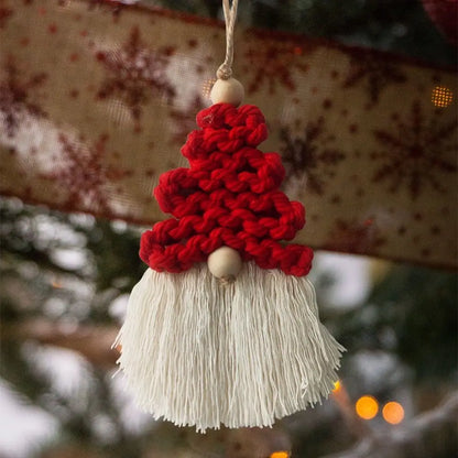 Knitted gnome macrame ornament with red hat and white beard hanging on a Christmas tree.