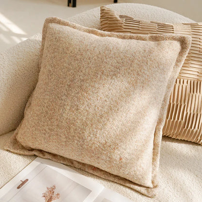 Beige textured pillow on a couch with a woven basket in the background