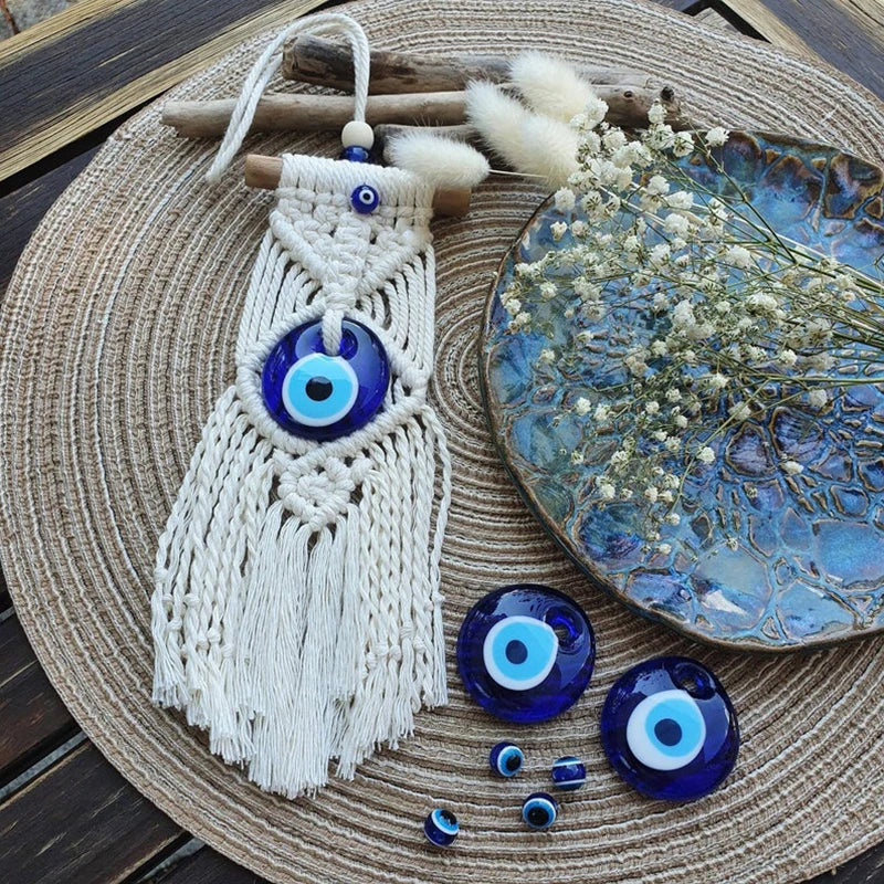 Macrame wall hanging with blue evil eye beads on a woven mat with dried flowers and a ceramic plate.