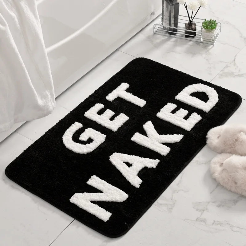 Black bath mat with 'GET NAKED' text in a bathroom setting boho home decor, bathroom rug, tufted bath mat, Get Naked rug, colorful shower mat, apartment decor, dorm bathroom accessories, housewarming gift, microfiber bath mat, fun bathroom rug, American style bath mat
